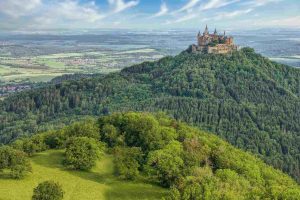 Germania. Foto di un paesaggio con una foresta lussureggiante e un castello in cima a una collina.