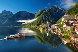 Austria. Veduta di un lago ai piedi delle Alpi, con una barca nei pressi di un paesino.