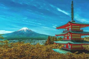 Giappone. Foto con un tempio giapponese tradizionale rosso con vista sul vulcano Fuji con la neve sulla cima.